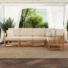 a couch sitting on top of a wooden floor next to a white curtained wall