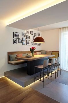 a living room with pictures on the wall and a dining table in front of it