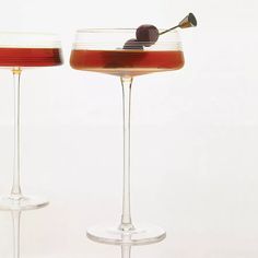 two wine glasses filled with liquid and an olive