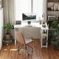 a desk with a computer on top of it in front of a window next to a potted plant