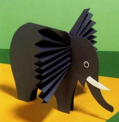 an elephant made out of black paper on a yellow and green background