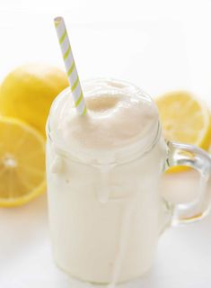 a glass with a straw in it next to lemons