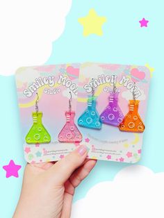 someone is holding up some colorful earrings in front of a blue and pink background with stars