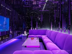 purple couches and tables in a room with neon lights on the ceiling above them