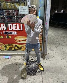 a man standing on the sidewalk holding a fan in front of a fast food store