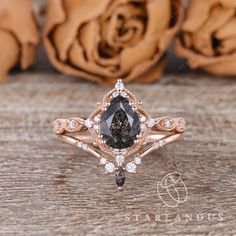 an engagement ring with a pear shaped black diamond surrounded by white and rose gold diamonds