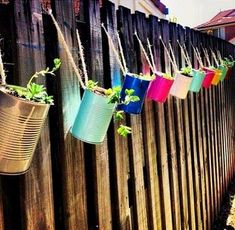 several hanging planters on the side of a wooden fence