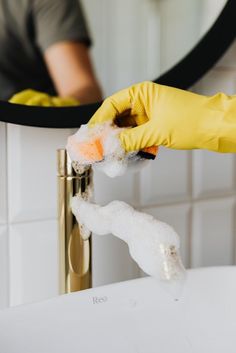 a person in yellow gloves cleaning a sink