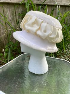 "This is an original 1940s-1950s faux fur cloche hat, milliner unknown. It features a gathered white satin ribbon around its crown, atop a broad white grosgrain ribbon all around (see images). This would have been appropriate wear for most any formal occasion (like weddings), but also many informal occasions, such as garden parties, worship services, pointing to the accused from the witness stand, etc. The circumference on the inside is 22 inches, which equates to (of course) a USA women's size 22 or a size 7 (if that sizing scale is more familiar to you). The depth of the hat is 5.5\" from brim to crown, and it is meant to encircle the head, not simply lie atop it. That said, if the wearer has a great deal of hair to pile up inside, a hat pin might help to secure it in place. There is a l Cream Cloche Hat For Evening, Cream Mini Hats For Vintage Events, Classic Fitted Cream Cloche Hat, Vintage Cream Mini Hat For Formal Events, Vintage Cream Mini Hat For Formal Occasions, Vintage Winter Cloche Hat For Wedding, Vintage White Costume Hat For Formal Occasions, Elegant Cream Cloche Hat For Winter, White Fitted Cloche Hat For Formal Occasions