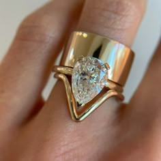 a woman's hand holding a ring with a large diamond in the middle and a gold band around it