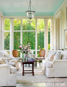 the living room is decorated in white and has blue walls, windows, and furniture