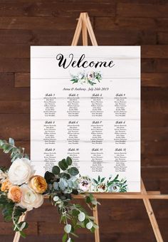 a welcome sign with flowers and greenery is displayed in front of a wooden wall