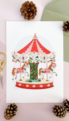 a merry go round christmas card with pine cones, scissors and other holiday decorations on the table