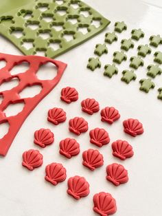 several different shapes and sizes of cookie cutters on a white table with red and green icing