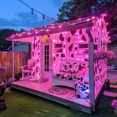 a small pink house with lights on the roof and furniture in the front yard at night