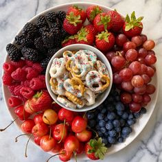 a white plate topped with fruit and pretzels on top of a marble counter