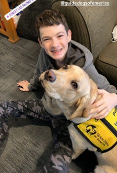 a boy sitting on the couch with his dog wearing a life jacket and smiling at the camera