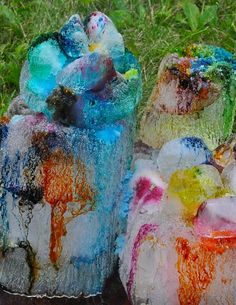 three different colored ice sculptures sitting in the grass