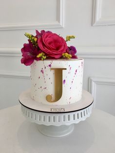 a white cake with pink and purple flowers in the letter j on it's side