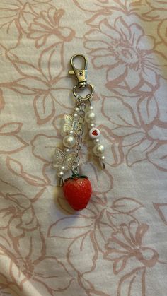 a key chain with a strawberry hanging from it's side on top of a table cloth