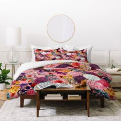 a bed covered in a colorful comforter next to a table