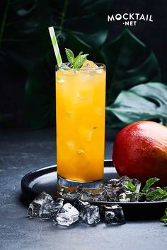 a drink with ice and an apple on a tray next to some minty garnish