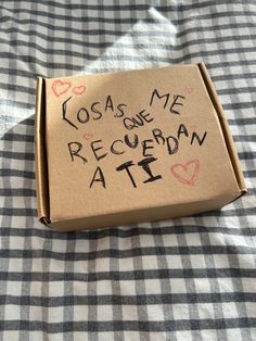 a cardboard box with writing on it sitting on a checkered tablecloth covered bed