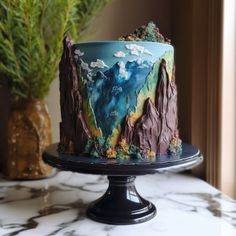 there is a cake on the table with mountains and clouds painted on it's side