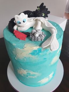 there is a blue cake with white frosting on the top and two black cats