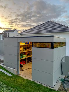 an open garage door on the side of a house with grass in front of it