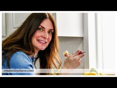 a woman sitting at a table with food in her hand and looking into the camera