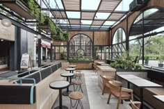 the inside of a restaurant with wooden tables and chairs, plants hanging from the ceiling