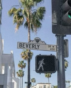 there is a street sign that says beverly on it and palm trees in the background