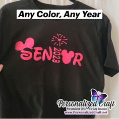 someone is holding up a black shirt with pink letters on it that says, any color, any year