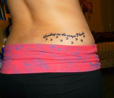 a woman's lower back tattoo with words on it