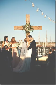 a bride and groom kissing in front of a cross at the end of their wedding ceremony