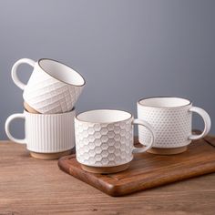 three white coffee cups sitting on top of a wooden tray next to a cup holder