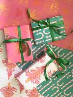 presents wrapped in pink, green and white wrapping paper with bows on the top are laying next to each other