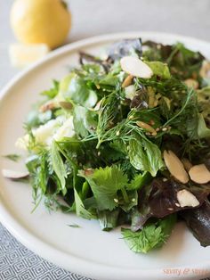 a white plate topped with greens and almonds