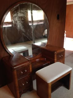 a dressing table with mirror and stool in front of it on carpeted flooring