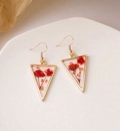 two triangle shaped earrings with red flowers on them