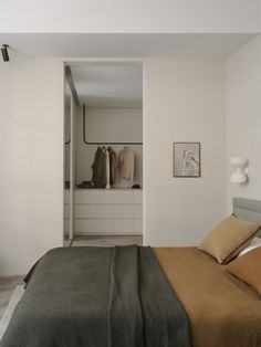 a bed sitting next to a window in a bedroom under a white curtain and light fixture