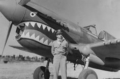 a man standing in front of an airplane with teeth painted on it's side