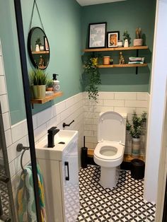 a small bathroom with green walls and black and white tile flooring on the wall