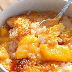 a close up of a bowl of food with fruit on top and a spoon in it