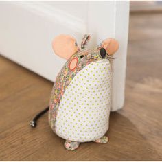 a toy mouse sitting on the floor next to a door way with polka dot fabric