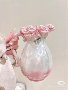 a person holding a pink vase with roses in it and a ring on the handle