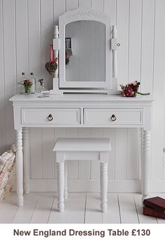 a white dressing table with a mirror, stool and candle on the floor next to it