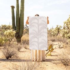 a person standing in front of a cactus with a towel on their back, covering his face