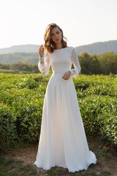 a woman in a white dress posing for the camera with her hands on her hips